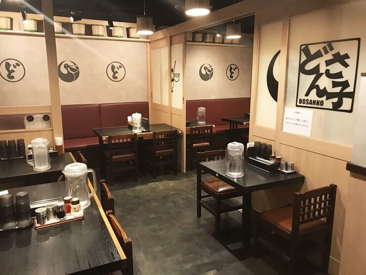 リブランディングした新しい『どさん子』内観 テーブルは黒、壁は白で丸いペリカンのロゴが黒で描かれている。 東京・大手町店 ※写真提供：アスラポート株式会社
